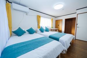 two beds in a hotel room with blue pillows at WAKE Inn 府中 in Fuchu