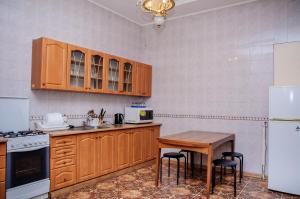 a kitchen with wooden cabinets and a table and a refrigerator at Golden Globus Hostel in Kyiv