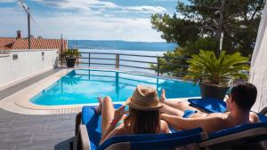 a man and a woman sitting in chairs next to a swimming pool at Villa Marina in Omiš