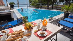 una mesa con comida y bebida junto a una piscina en Villa Marina, en Omiš
