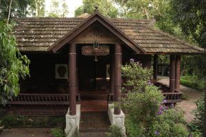a small building with a roof in a garden at Periyaveettil Heritage in Neyyāttinkara