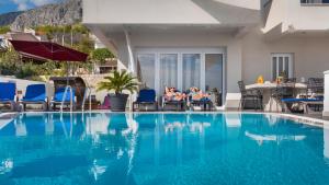 two people sitting in chairs next to a swimming pool at Villa Marina in Omiš