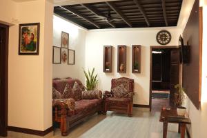 a living room with two chairs and a clock at Periyaveettil Heritage in Neyyāttinkara