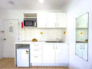 a kitchen with white cabinets and a microwave at Tropic Haven in Airlie Beach