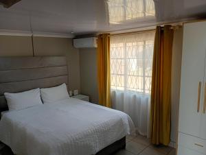 a bedroom with a white bed and a window at Ashdown BnB in Pietermaritzburg