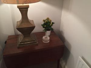 a table with a lamp and a vase of flowers on it at The Fox and Hounds in Oakham