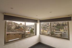 a room with three windows with views of a city at The Castle Star in Amman