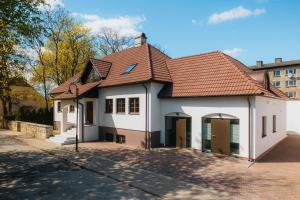 a white house with a red roof on a street at Komandandi City Center Apartments in Kuressaare