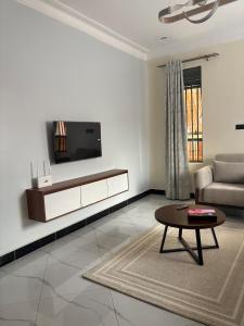 a living room with a couch and a tv on a wall at Sunset Hideout Kulambiro in Kampala