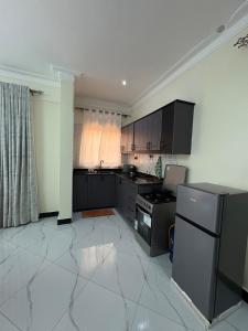 a kitchen with black cabinets and a white tile floor at Sunset Hideout Kulambiro in Kampala