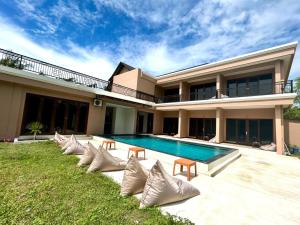 a house with a swimming pool and some chairs at Airindah Villa in Gili Islands