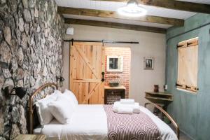 a bedroom with a bed and a stone wall at Die Stalle by Chickania in Jacobs Bay