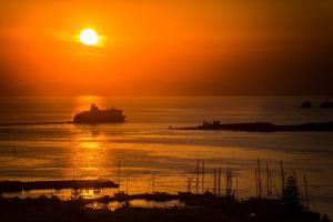 a boat in the ocean at sunset at Sunset View Hotel in Parikia