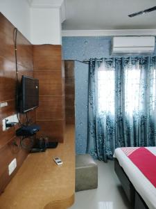 a bedroom with a bed and a tv and curtains at Sun Classic Residency in Chennai