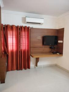 a room with a desk with a television and red curtains at Sun Classic Residency in Chennai +6 photos