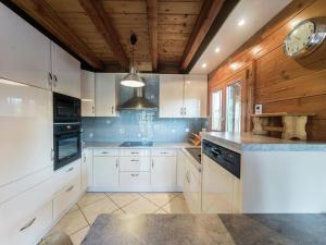 a kitchen with white cabinets and a wooden ceiling at Chalet in Vosges with Sauna & Panoramic Views in Anould