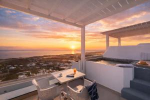 a balcony with a table and chairs and a sunset at La Estrella Luxury Suites in Vourvoúlos