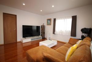 a living room with a couch and a flat screen tv at Tomi house in Kariya