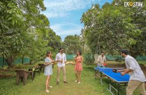 a group of people standing around a ping pong table at EKOSTAY - Forestwood Villa in Alibaug