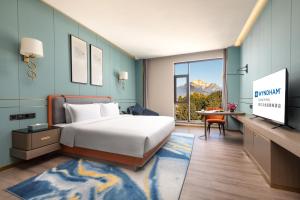 a hotel room with a bed and a television at Wyndham Lijiang Yulong in Lijiang