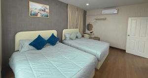 two beds in a hotel room with blue pillows at Sea Flower Onsen in Ban Bo Khaem +5 photos