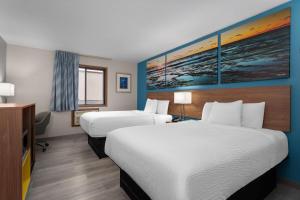 a hotel room with two beds and a tv at Days Inn by Wyndham Austin in Austin