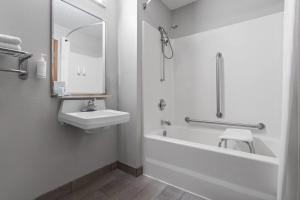 a white bathroom with a sink and a tub and a toilet at Days Inn by Wyndham Austin in Austin +26 photos