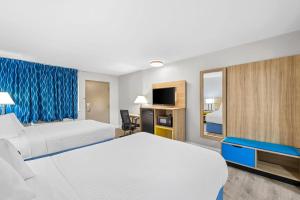 a hotel room with two beds and a television at Days Inn by Wyndham Chesapeake in Chesapeake