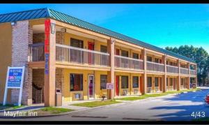 a large yellow building with balconies on a street at Mayfair Inn in Williamston