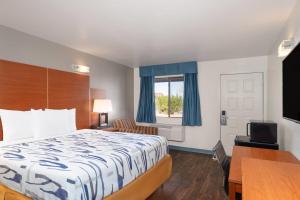 a hotel room with a bed and a desk at Travelodge by Wyndham Albuquerque West in Albuquerque
