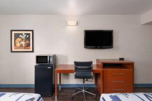 a room with a desk and a tv on a wall at Travelodge by Wyndham Albuquerque West in Albuquerque