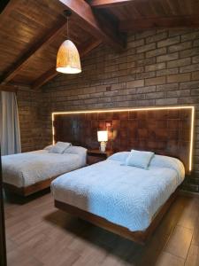 a bedroom with two beds and a brick wall at cabañas el rio alcatraz in Zacatlán