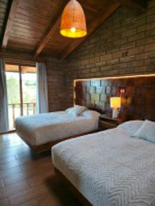 a bedroom with two beds and a large window at cabañas el rio alcatraz in Zacatlán