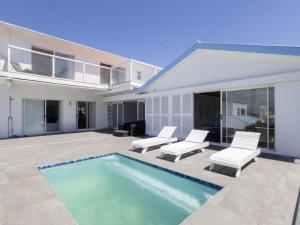 a house with a swimming pool and two white chairs at Villa Mykonos in Cape Town