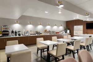 a restaurant with tables and chairs and a kitchen at Wingate by Wyndham Clearfield in Clearfield