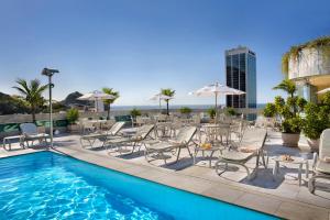 a swimming pool with chairs and a table and a pool at Windsor Plaza Copacabana in Rio de Janeiro