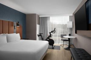 a hotel room with a bed and a room with a gym at Tempo By Hilton Pigeon Forge in Pigeon Forge