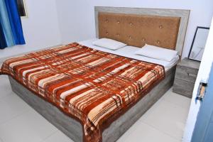 a bedroom with a bed with an orange and brown comforter at Nirmala Garden in Bamiana