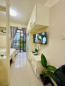 a bedroom with a bed and a tv on a wall at STUDIO WITH BALCONY at the HEART of DAVAO CITY in Davao City