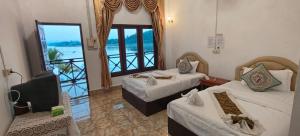 a hotel room with two beds and a balcony at Phonevichith Riverside Hotel Houayxai in Ban Khonkèo