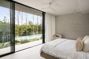 a bedroom with a large window with a view of a pool at Latitude 156 - Elevated Luxury Overlooking the Greens in Doonan