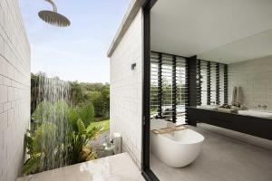 a bathroom with a tub and a sink and a toilet at Latitude 156 - Elevated Luxury Overlooking the Greens in Doonan