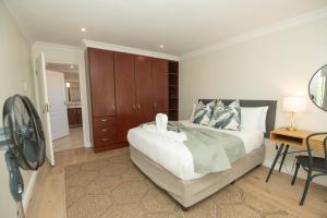 a bedroom with a bed and a desk and a fan at Brooklands Sanctuary in Gqeberha