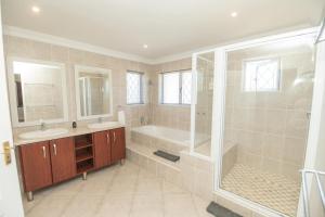 a bathroom with two sinks and a tub and a shower at Brooklands Sanctuary in Gqeberha +30 photos