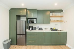 a kitchen with green cabinets and a refrigerator at Brooklands Sanctuary in Gqeberha
