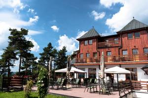 a building with tables and chairs in front of it at Hotel Vítkova Hora - Veitsberg in Karlovy Vary