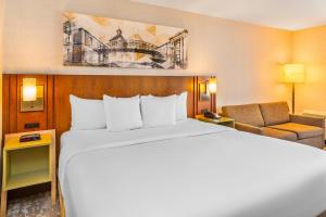 a hotel room with a large bed and a chair at Comfort Inn Hamilton - Stoney Creek in Hamilton
