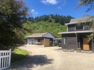 a house with a white fence next to a driveway at The Cottage in Waikawa in Waikawa