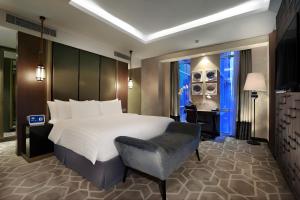a bedroom with a large bed and a chair at Aston Priority Simatupang Hotel and Conference Center in Jakarta