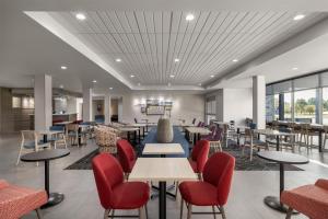 a dining room with tables and chairs and windows at Home2 Suites By Hilton Muncie in Muncie